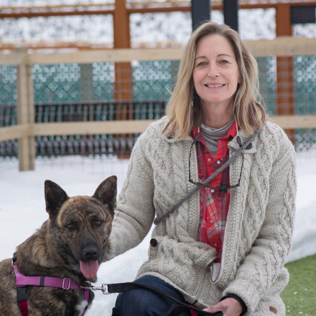 Heidi Hayes sitting outside in winter weather with her brindled dog next to her
