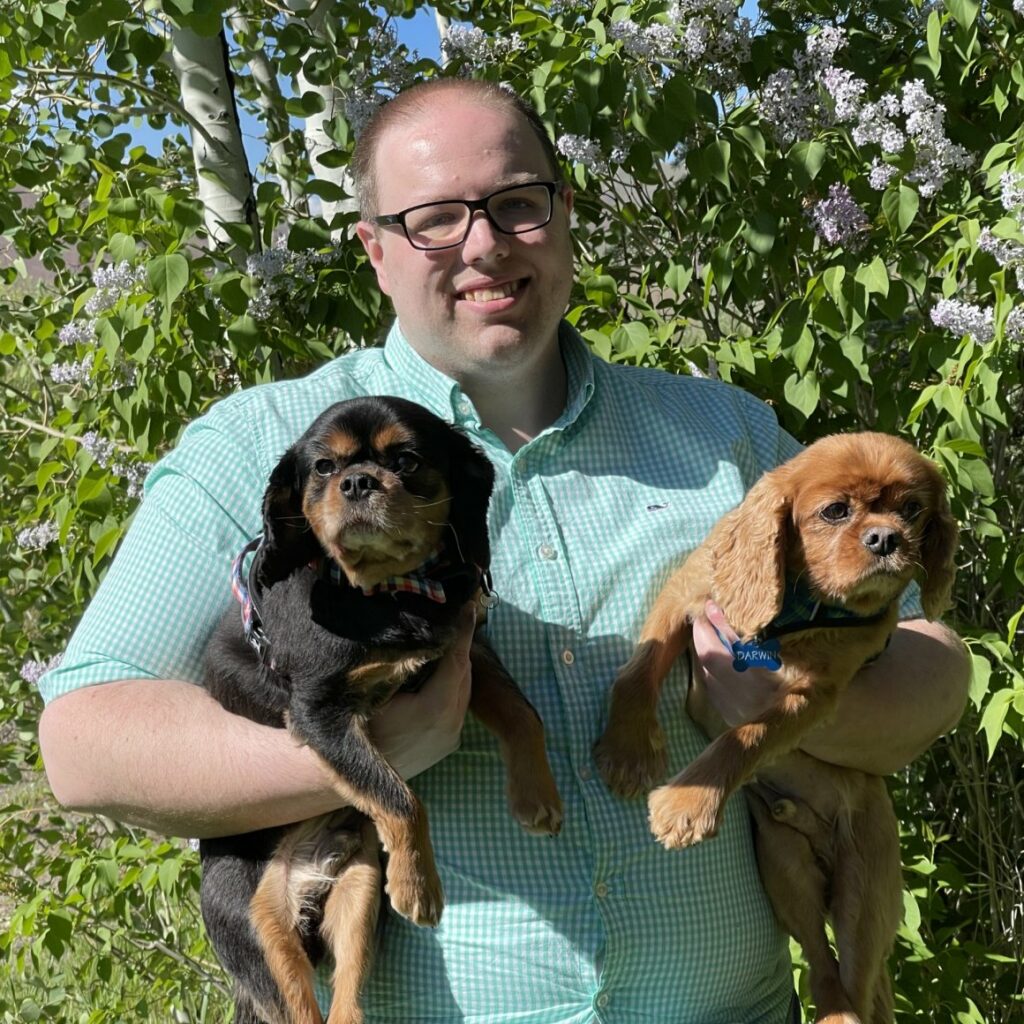 Brent Householder standing outside holding two small dogs, one in each arm