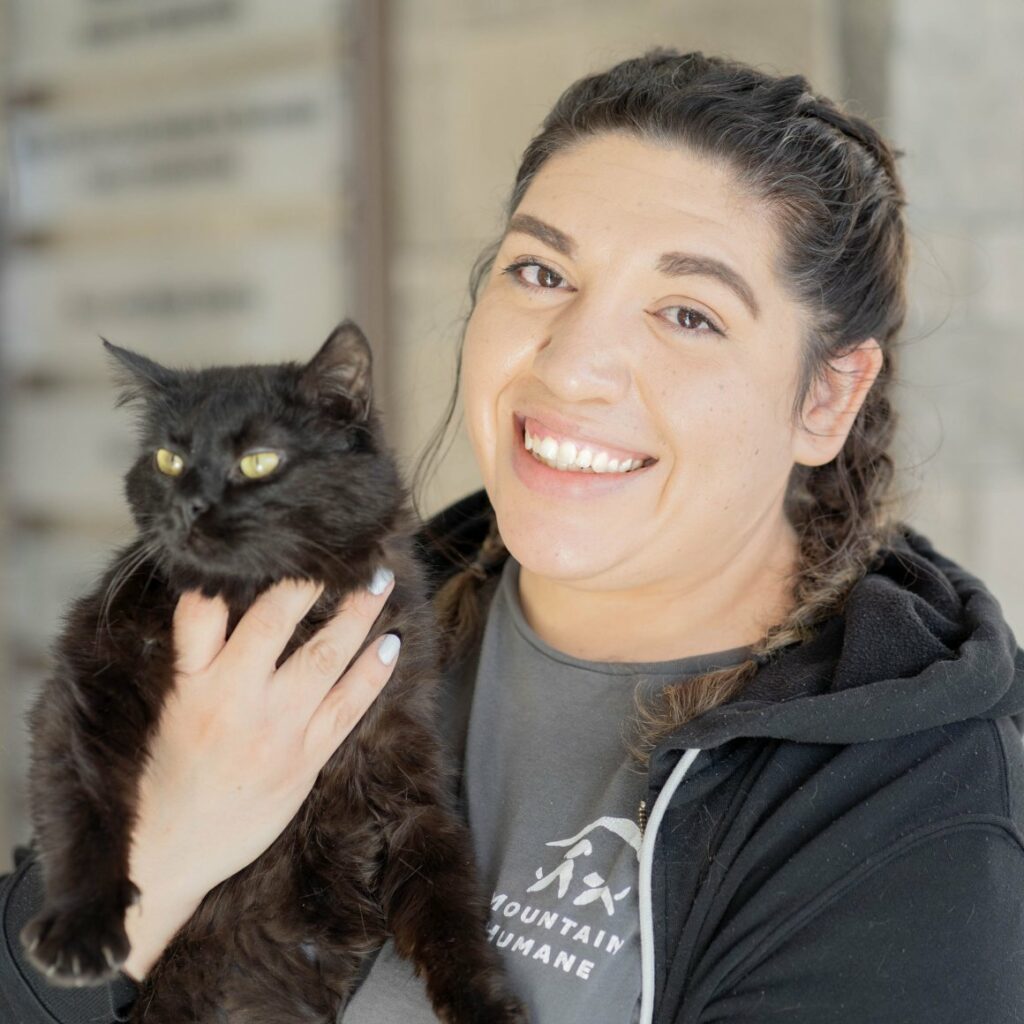 Pita Vega holding up a fluffy black cat while smiling