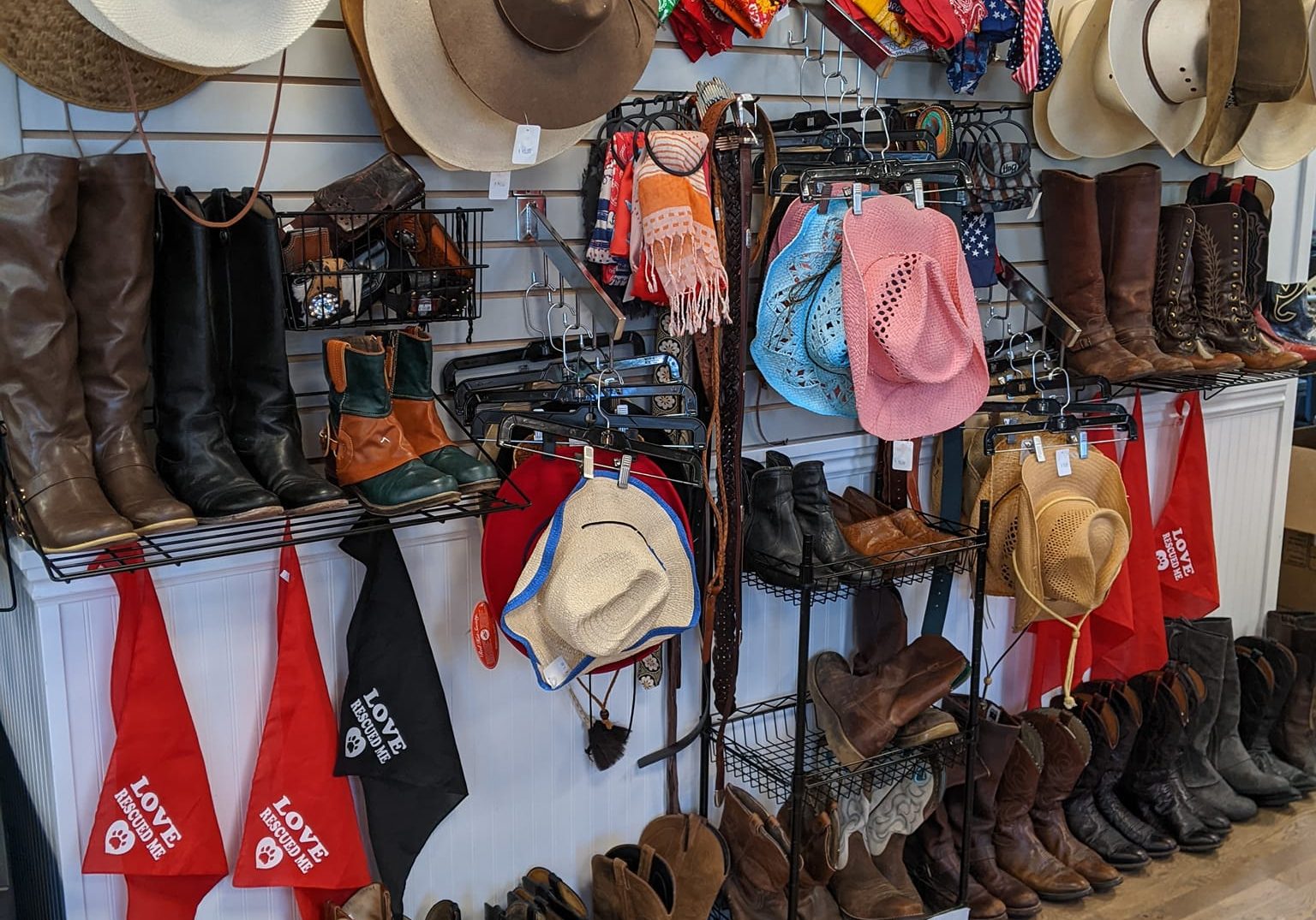 An assortment of hats, shoes, scarves, and other accessories hanging on the wall at the Barkin' Thrift store